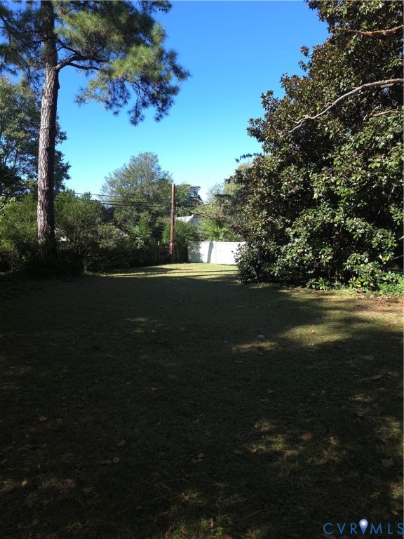 Expansive backyard featuring a level lawn, mature trees, and perimeter fencing