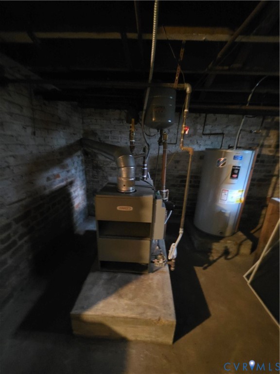 Mechanical area featuring a furnace, water heater, metal ducting, and exposed brick masonry