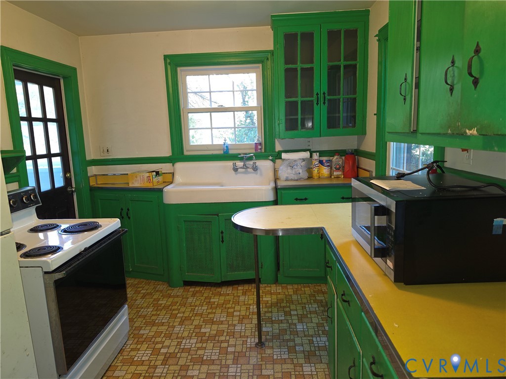 Kitchen featuring a porcelain apron-front sink, wall-mounted faucet, glass-front upper cabinetry, yellow laminate countertops, and patterned resilient flooring
