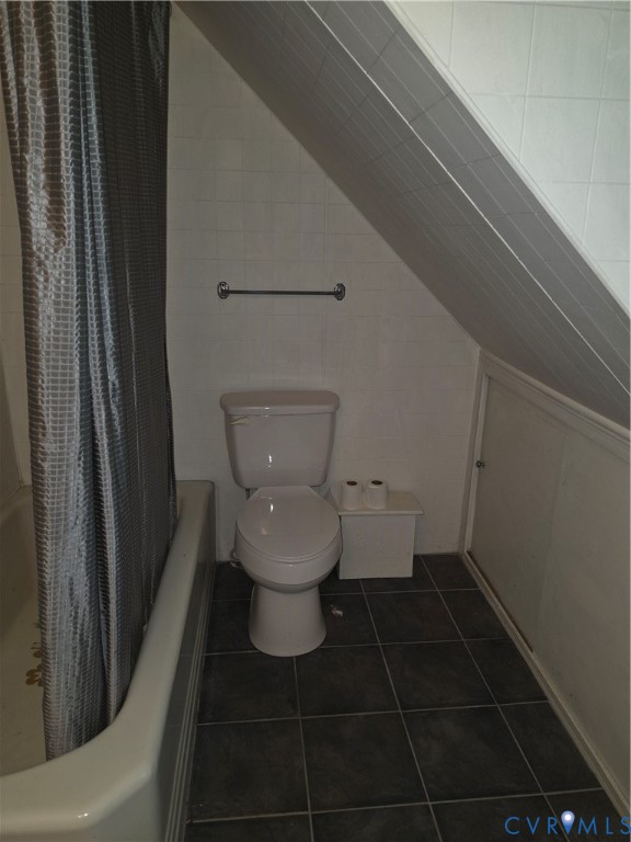 Bathroom featuring dark square tile flooring, white wall tiling, a sloped ceiling, and an integrated access panel