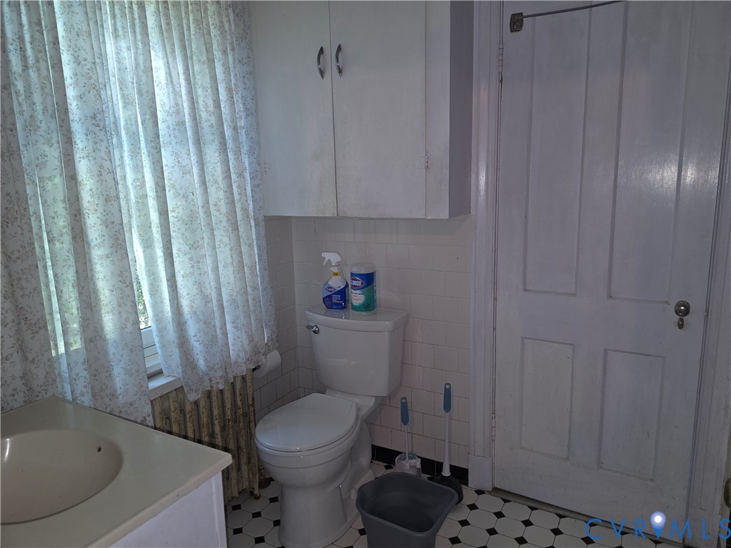 Wall-mounted cabinetry, square ceramic wall tile, classic hexagonal floor tile, and a four-panel solid wood door