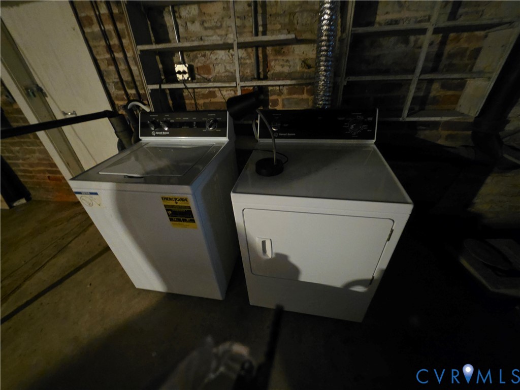 Dedicated laundry area featuring exposed brick masonry walls and built-in industrial-style shelving