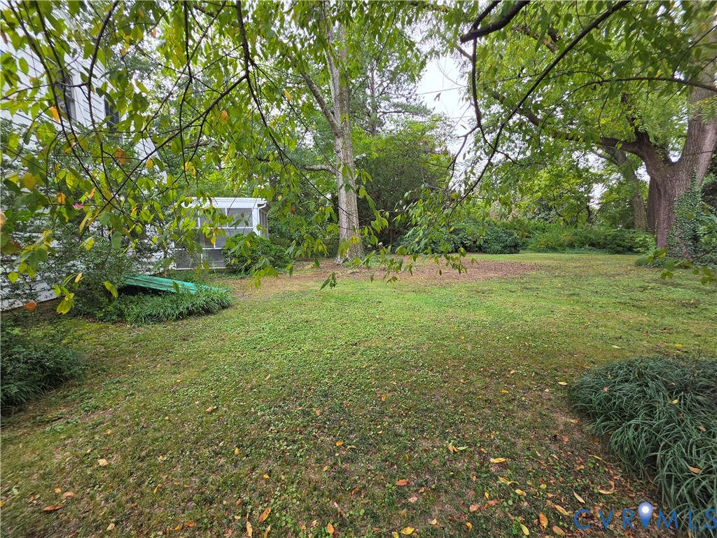 Expansive backyard featuring mature trees, established landscaping, and a detached screened structure