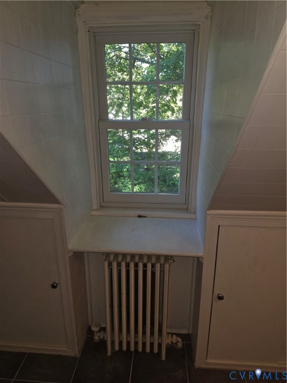 Multi-pane sash window with a deep sill, flanked by built-in cabinetry featuring recessed-panel doors and finished with a metallic radiator