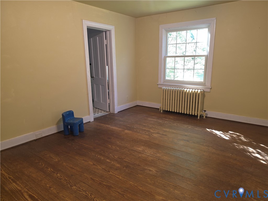 Hardwood flooring, multi-pane window with traditional casing, and cast-iron radiator