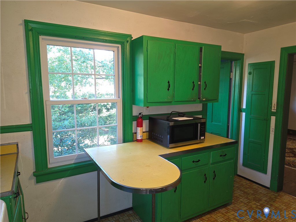 Kitchen featuring wood cabinetry, integrated countertop with metal edging, double-hung window, built-in wall paneling, and patterned flooring