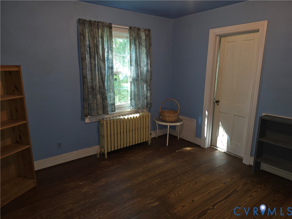 Wood-finish flooring, single-hung window with wood casing, and a four-panel interior door with traditional hardware