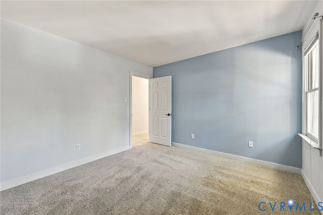 Generously sized bedroom featuring a soft blue accent wall, natural light, and flexible furniture placement.