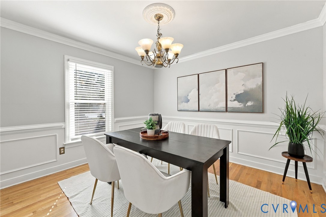 Bright dining room featuring timeless architectural details, hardwood floors, and a large window.