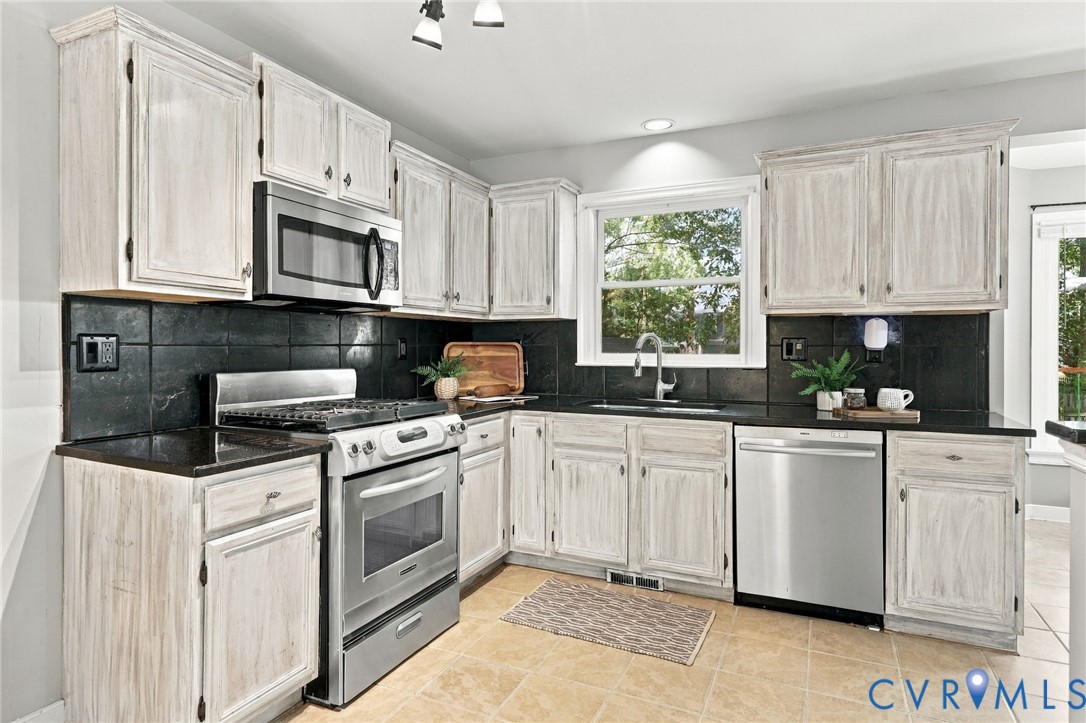 Kitchen with stainless steel range and built-in microwave, tile flooring, and ample cabinetry for storage.