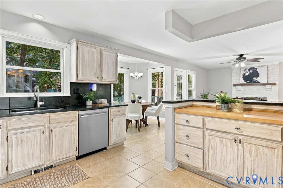 Spacious kitchen featuring distressed-finish cabinetry, dark countertops, stainless steel appliances, and a convenient breakfast bar overlooking the family room.