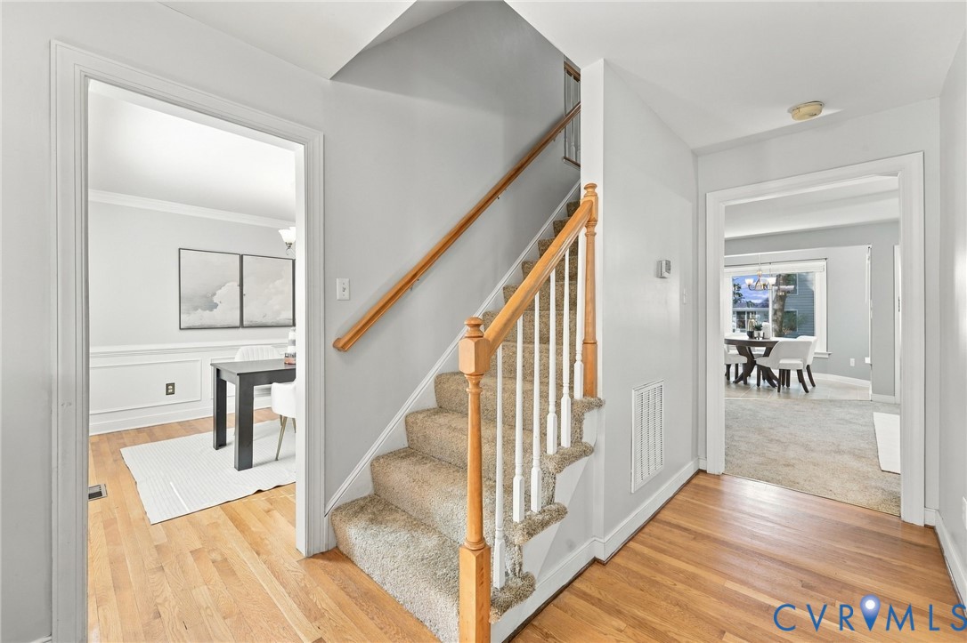 Spacious foyer with hardwood flooring and a central staircase with brand new carpet connecting the home's main living areas.