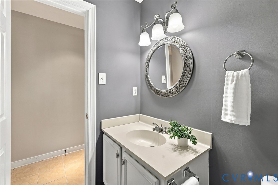 Main-level powder room featuring a single-sink vanity, decorative mirror, and updated light fixture.