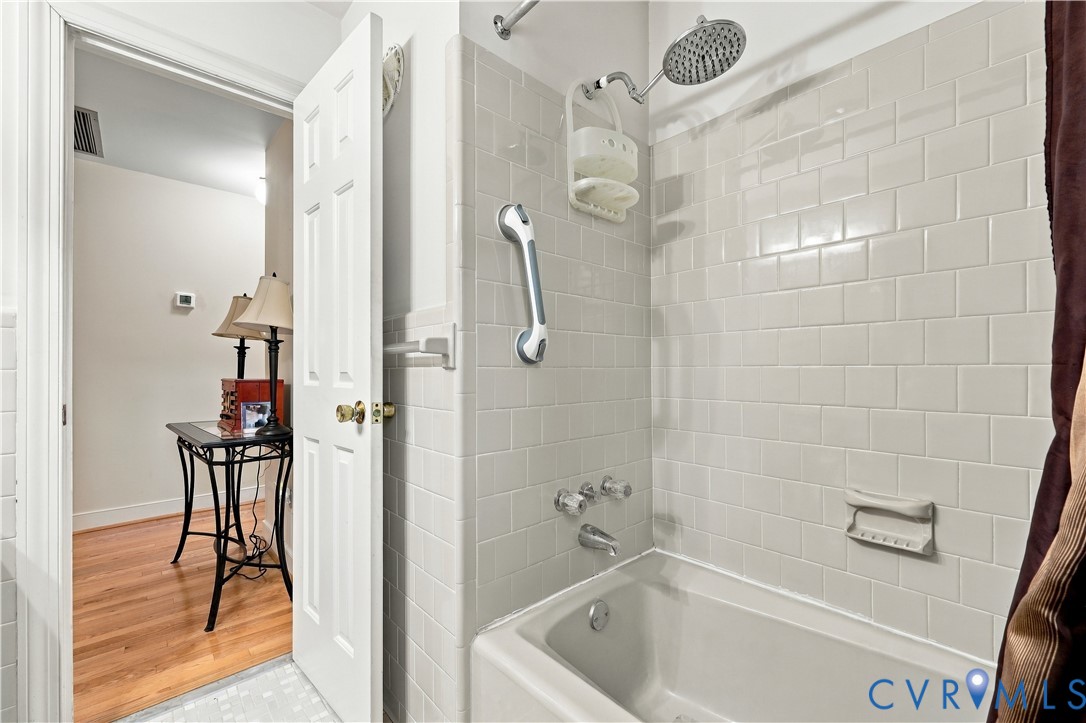 Full-height ceramic tile surround, integrated soaking tub, chrome finish shower fixtures, and polished hardware