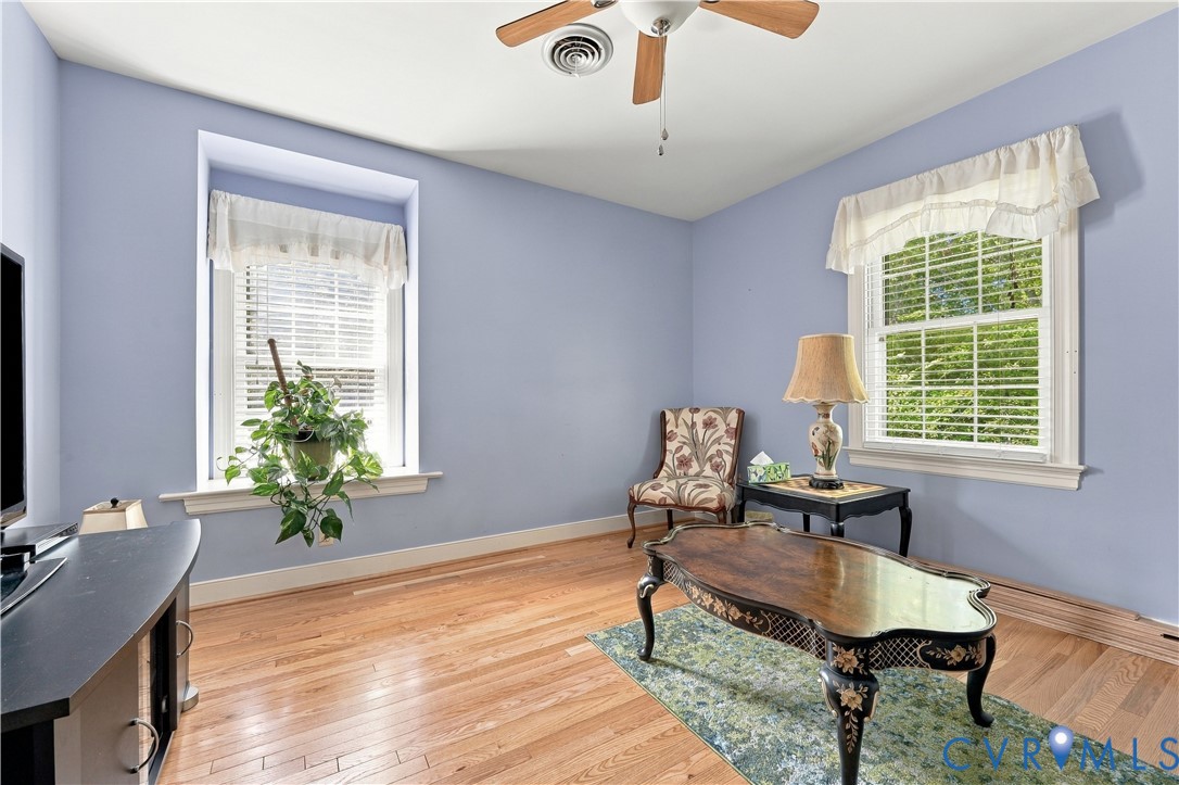 Hardwood flooring, dual-aspect windows with deep sills, and a central ceiling fan with integrated lighting