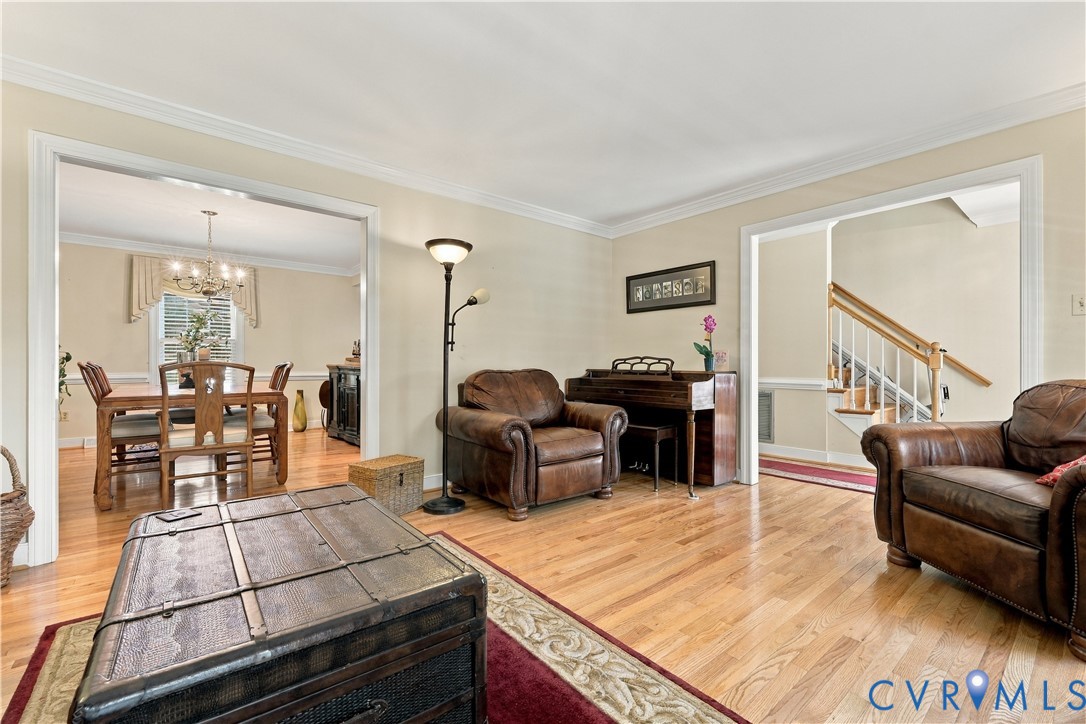 Living space featuring wood-finish flooring, crown molding, and cased openings