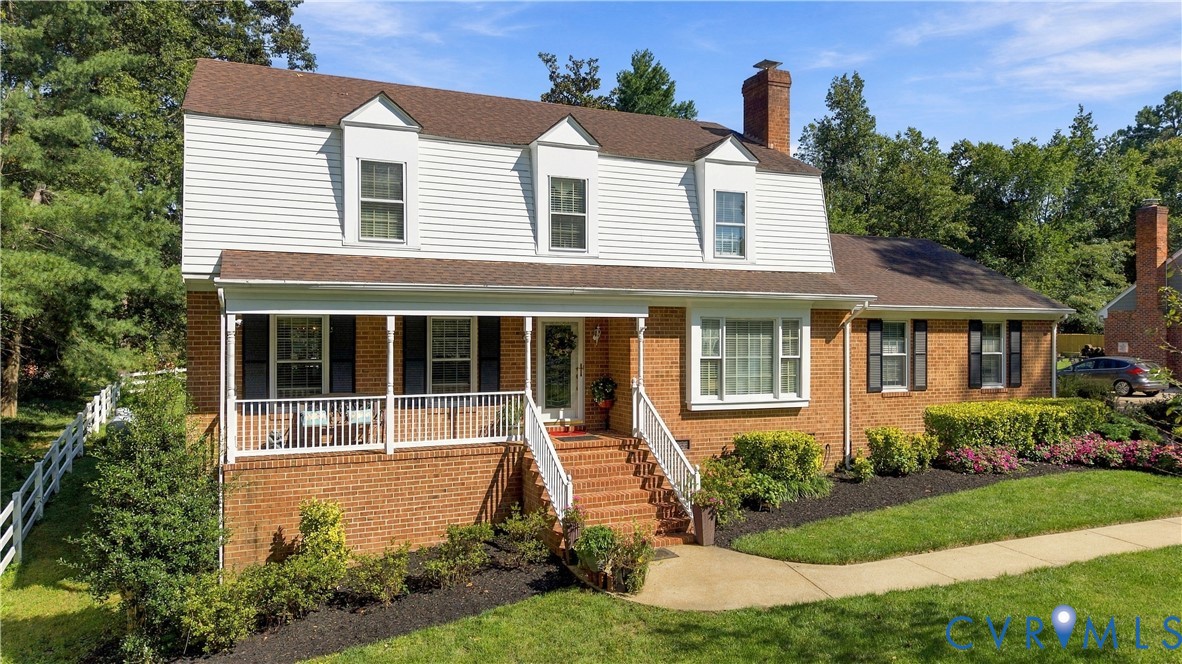 Dutch Colonial exterior featuring brick and siding facade, covered front porch with white railing, brick staircase, and multi-pane windows with shutters
