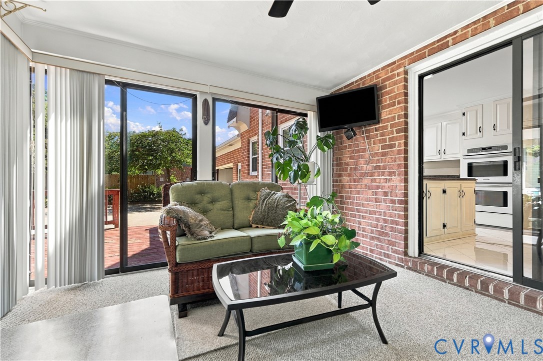 Sunroom featuring exposed brick walls, expansive floor-to-ceiling windows, and multiple glass sliding doors