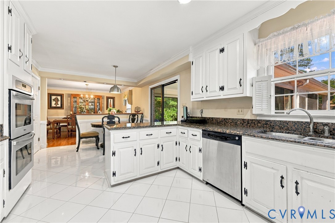Kitchen featuring white cabinetry, stone countertops, stainless steel double wall ovens, a stainless steel dishwasher, and polished tile flooring