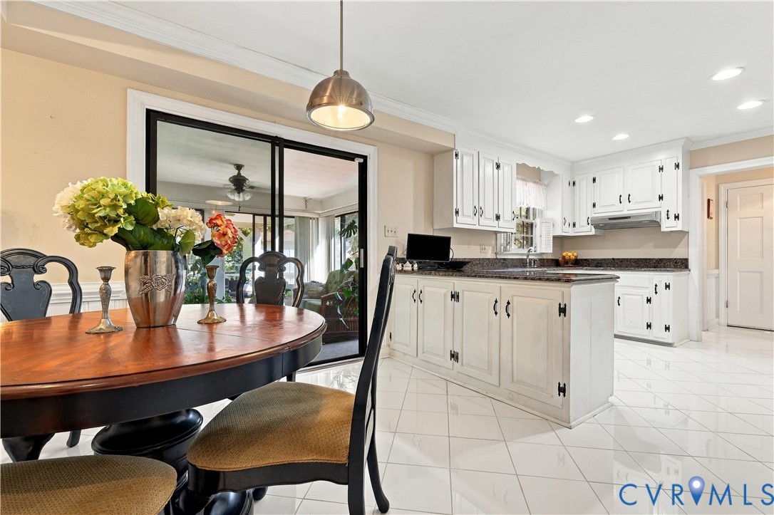 Kitchen featuring white cabinetry, dark stone countertops, tile flooring, recessed lighting, and a metal pendant fixture