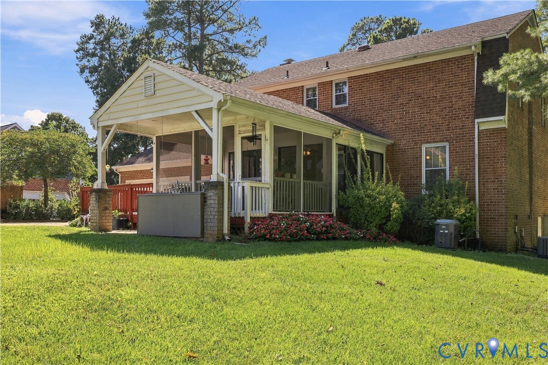 Brick exterior residence featuring a screened-in porch with gabled roof, wood-railing accents, and expansive lawn