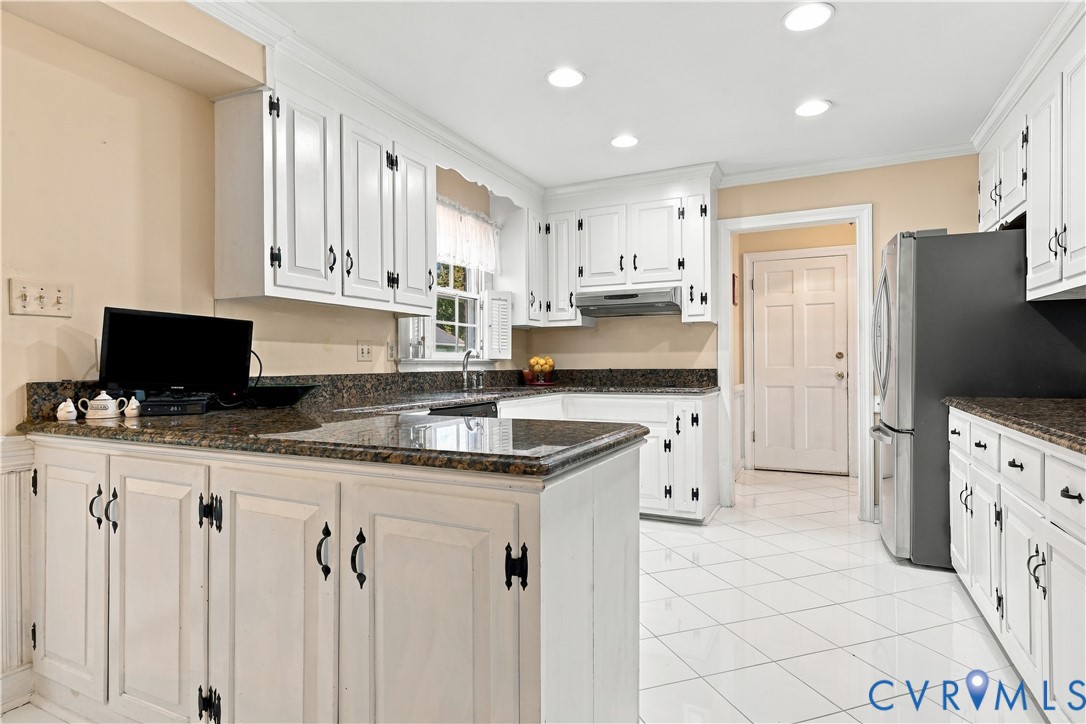 Kitchen featuring white cabinetry with black hardware, stone-composite countertops, recessed lighting, and tile flooring