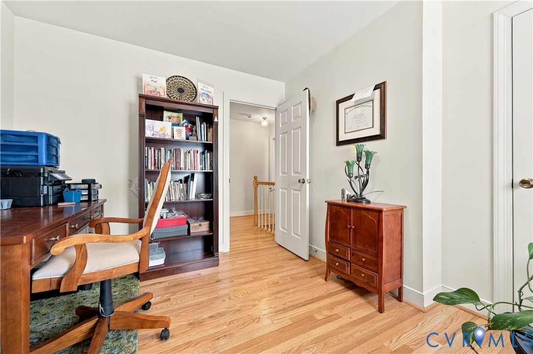 Room featuring wood-finish flooring, a six-panel interior door, and neutral wall paint
