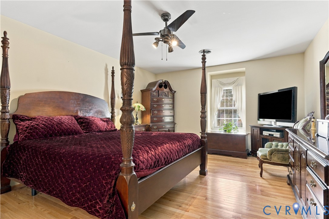 Room featuring wood-finish flooring, a centrally mounted ceiling fan with integrated lighting, and a window with deep-set casing