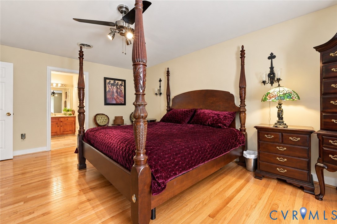 Hardwood flooring, wall-mounted light fixtures, and a multi-blade ceiling fan with integrated lighting