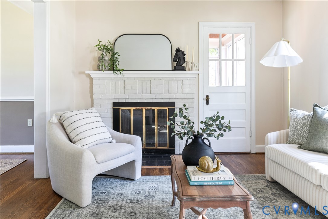 Painted brick fireplace with a decorative mantel, wood-finish flooring, and a multi-pane glass door Painted brick fireplace with a decorative mantel, wood-finish flooring, and a multi-pane glass door