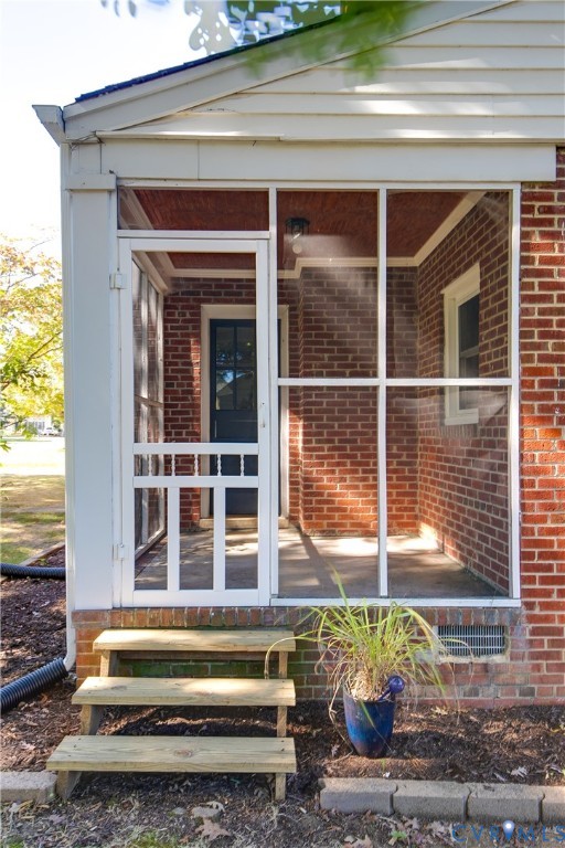Enclosed porch featuring a red brick exterior, white-framed screening, wood-tone ceiling finish, and three-step wooden staircase