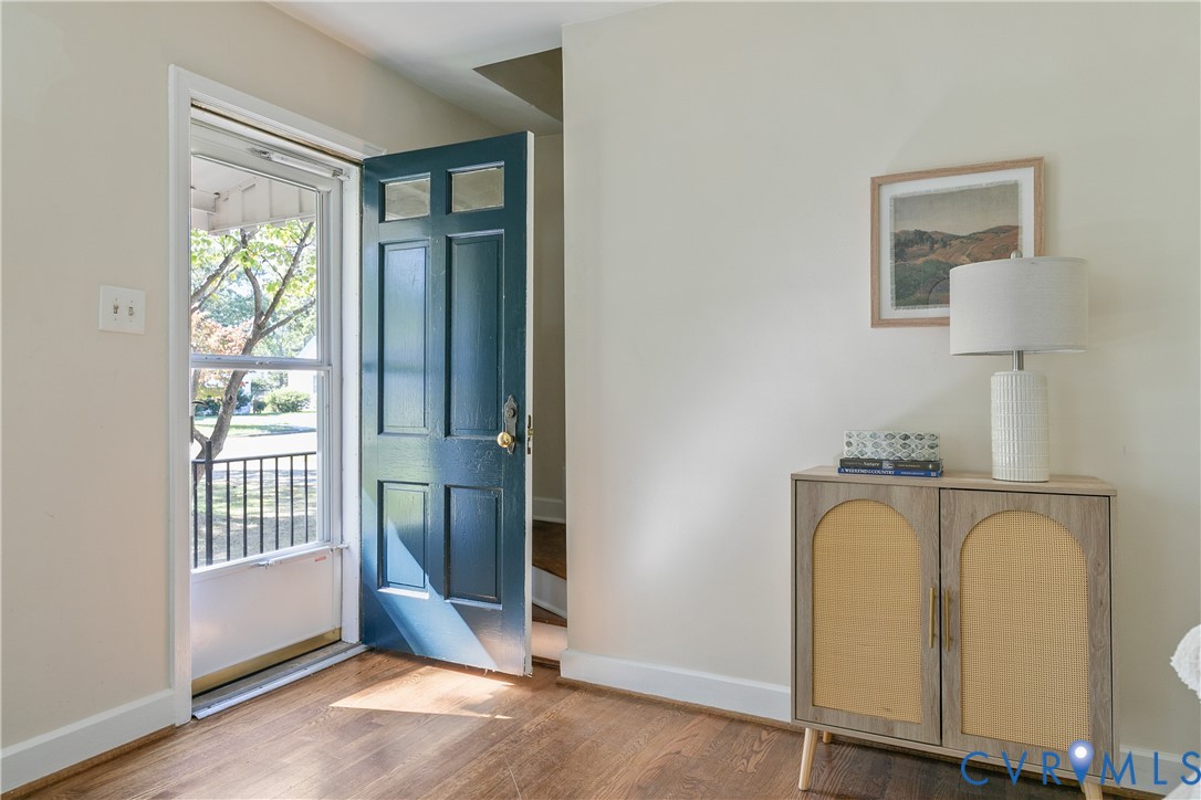 Entryway featuring wood-finish flooring, a painted panel door with upper glass inserts, and a white screen door Entryway featuring wood-finish flooring, a painted panel door with upper glass inserts, and a white screen door
