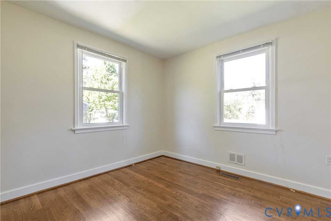 Interior space featuring wood-finish flooring, neutral wall tones, and two double-hung windows