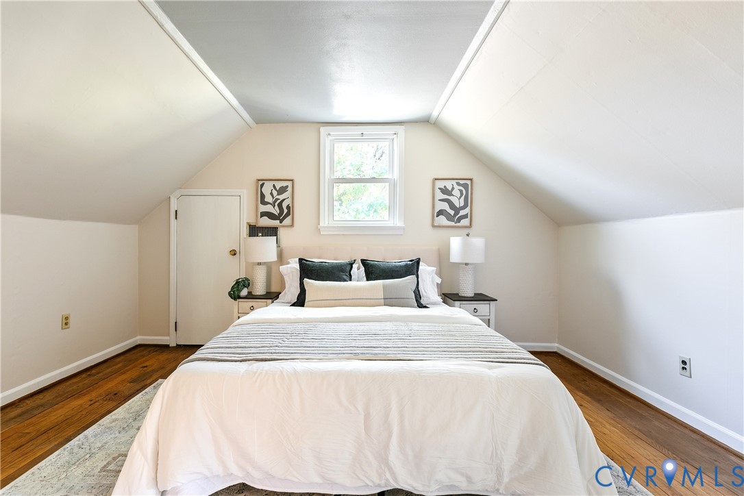 Sloped ceilings, wood-finish flooring, and a central window with paneled door access to storage
