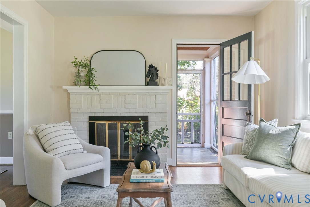 Painted brick fireplace with a mantel, wood-finish flooring, and a multi-pane glass-panel exterior door