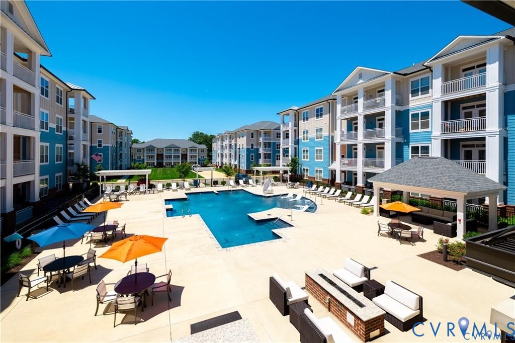 Swimming pool with stone-finished decking, covered gazebo, built-in masonry fire pit, and multi-story structures featuring private balconies Swimming pool with stone-finished decking, covered gazebo, built-in masonry fire pit, and multi-story structures featuring private balconies