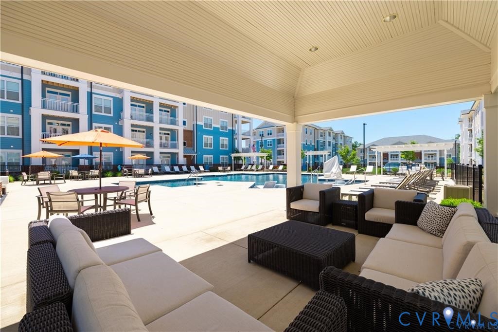 Covered outdoor lounge area with recessed lighting, concrete patio, and swimming pool