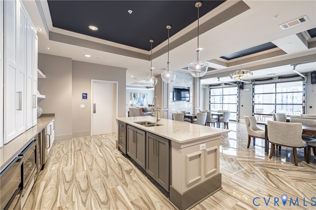 Kitchen featuring a center island with stone countertops, white cabinetry with silver hardware, recessed ceiling lighting, glass pendant fixtures, and large-format tile flooring Kitchen featuring a center island with stone countertops, white cabinetry with silver hardware, recessed ceiling lighting, glass pendant fixtures, and large-format tile flooring