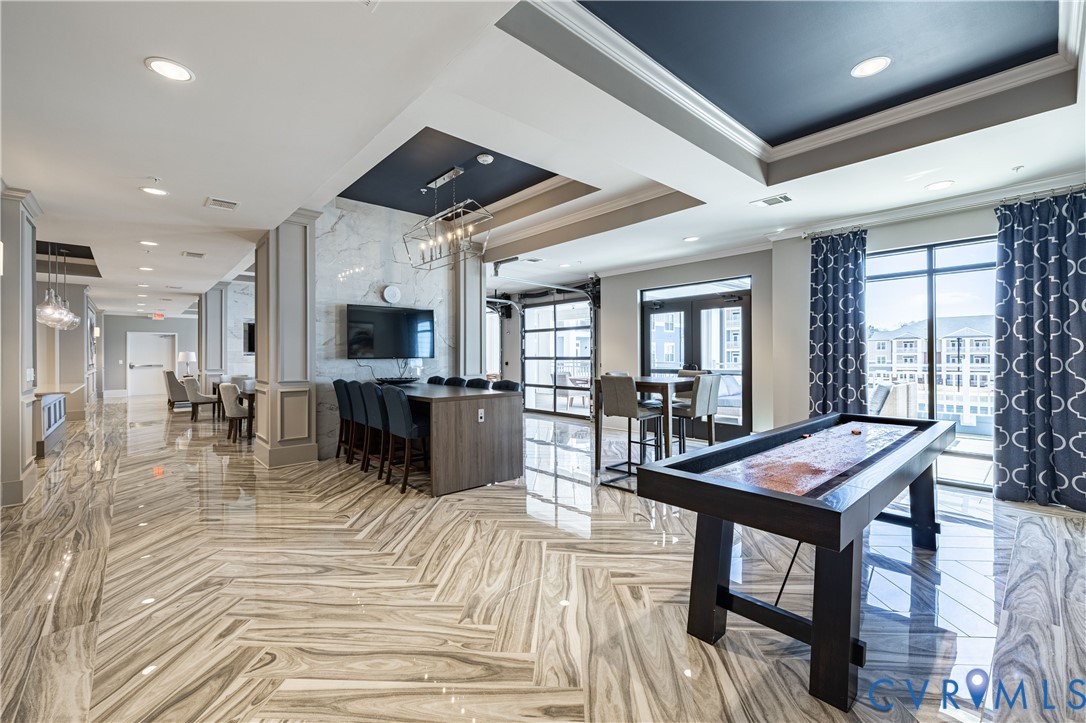 Polished stone flooring in a herringbone pattern, coffered ceilings with recessed lighting, integrated stone-clad wall feature, and glass-paneled garage-style door Polished stone flooring in a herringbone pattern, coffered ceilings with recessed lighting, integrated stone-clad wall feature, and glass-paneled garage-style door