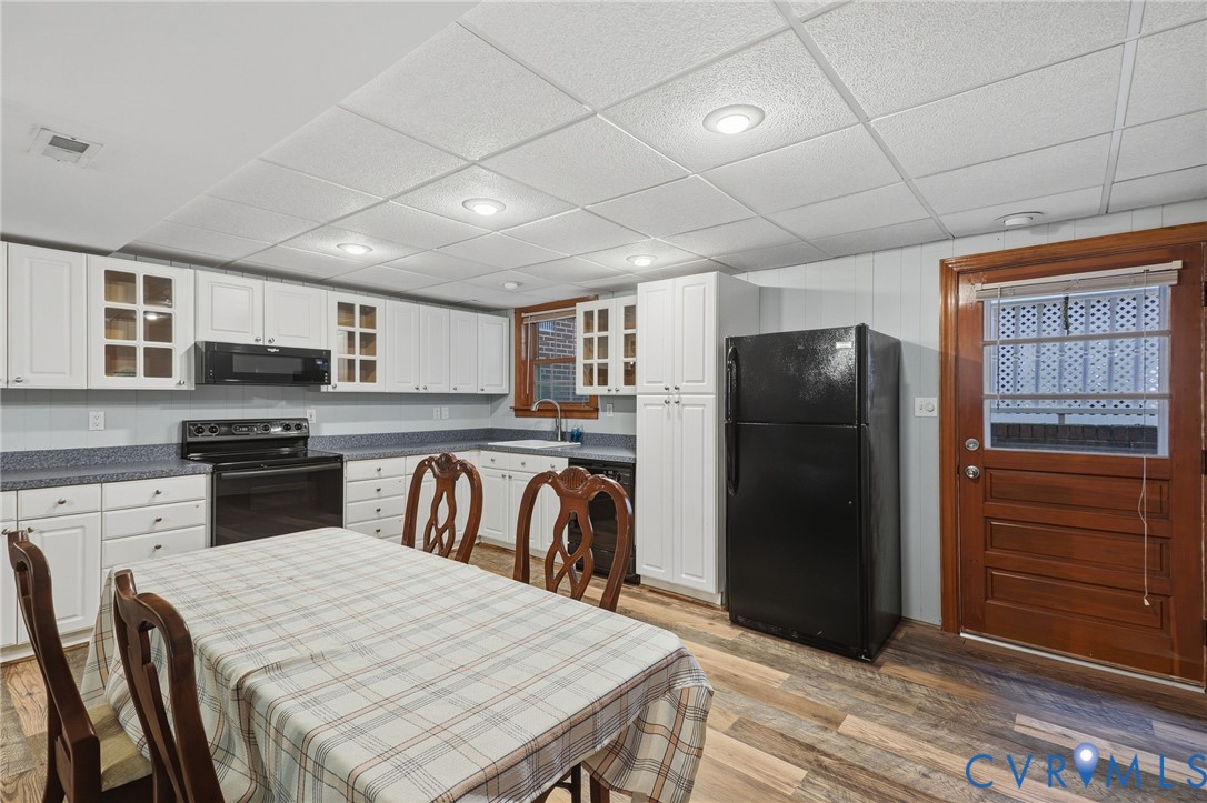 Kitchen featuring white cabinetry with glass-front uppers, solid surface countertops, recessed lighting, wood-finish flooring, and a solid wood exterior door