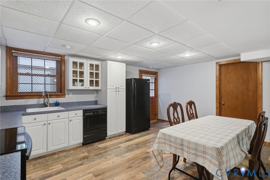 Kitchen featuring white cabinetry with glass-panel upper doors, solid-surface countertops, wood-finish flooring, recessed lighting, and an integrated drop-in sink