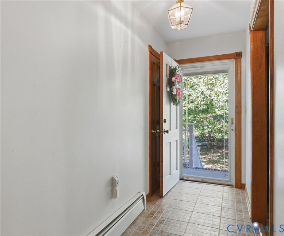 Entryway featuring tiled flooring, natural wood trim, a paneled door, and a glass-paneled storm door
