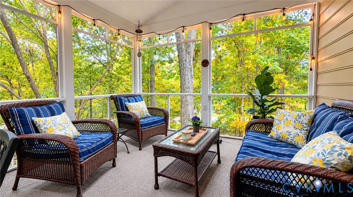 Screened porch featuring a beadboard ceiling, neutral carpeting, horizontal lap siding, and expansive floor-to-ceiling screens showcasing surrounding trees