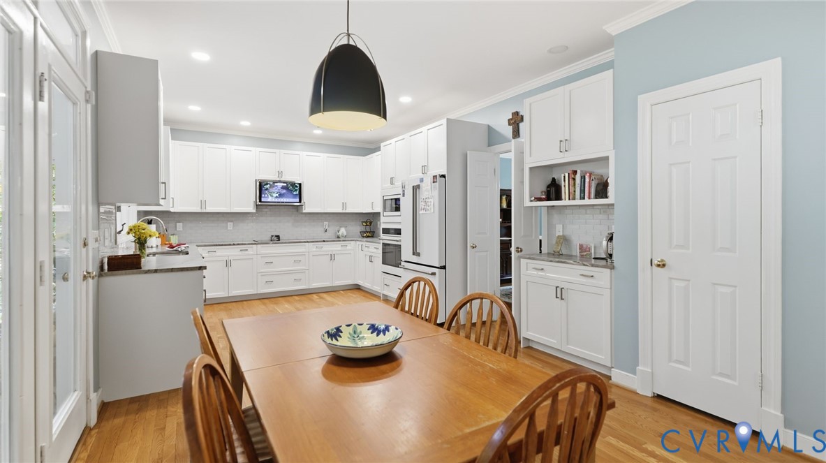 Kitchen featuring white cabinetry, stone-finish countertops, built-in double wall ovens, wood-finish flooring, and a dome-shaped pendant light fixture