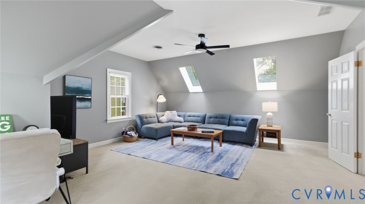 Vaulted ceiling with dual skylights, integrated ceiling fan, and recessed lighting