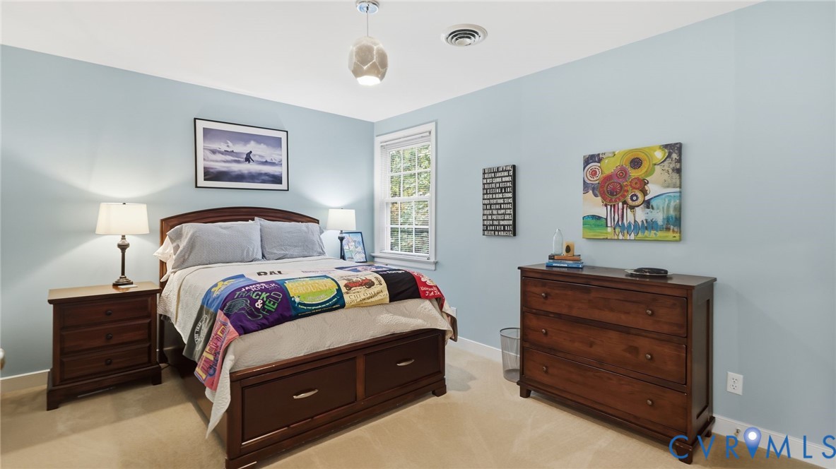 Bedroom featuring light blue wall paint, neutral carpeting, multi-pane window, and modern pendant lighting