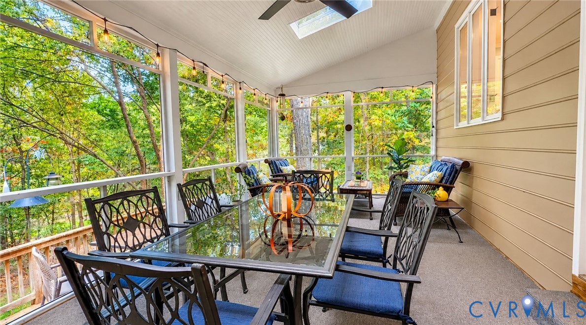 Screened porch featuring a vaulted beadboard ceiling, integrated skylight, ceiling fan, and horizontal siding
