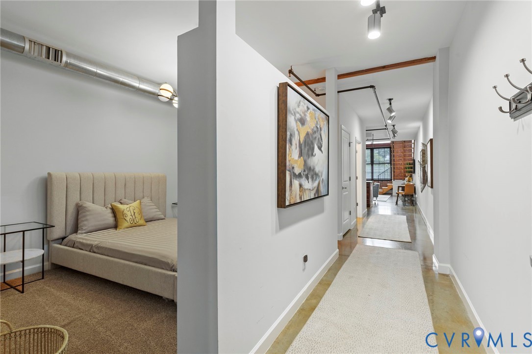 Industrial-style interior featuring exposed metallic ductwork, concrete flooring, exposed ceiling-mounted piping, adjustable track lighting, and a partial-height partition wall