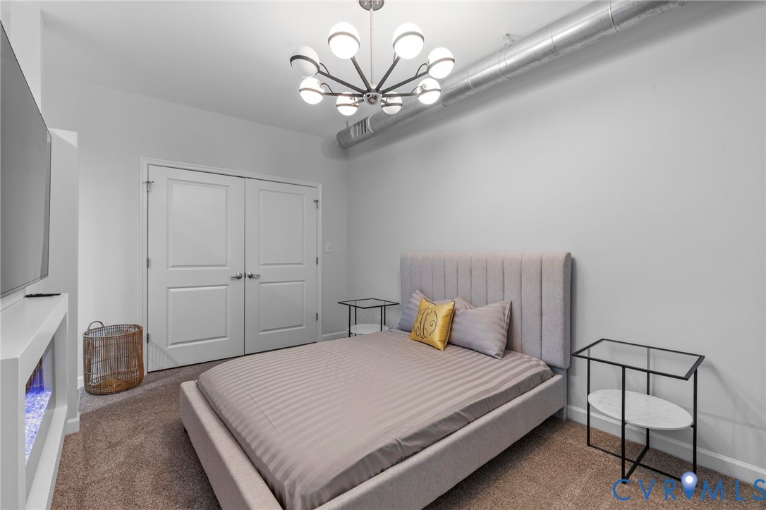 Industrial-style space featuring an exposed metal duct, contemporary multi-arm orb chandelier, built-in electric fireplace, and double-door closet