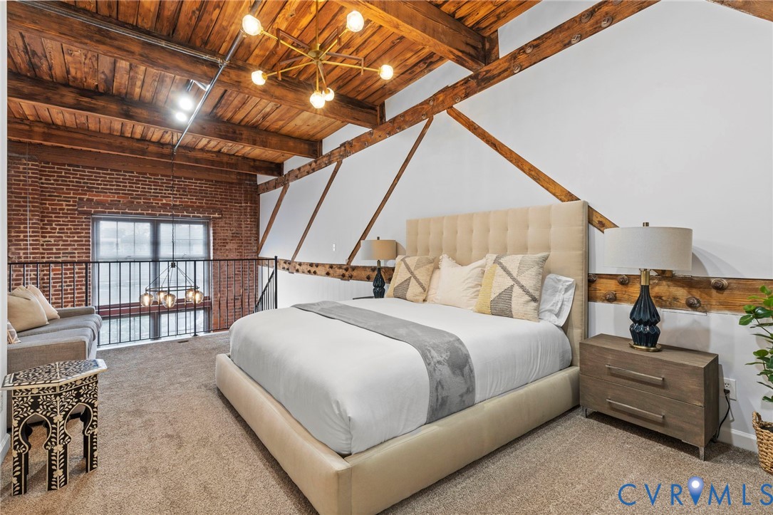 Exposed brick wall, vaulted ceiling with heavy timber beams, metal railing, and decorative wall bracing